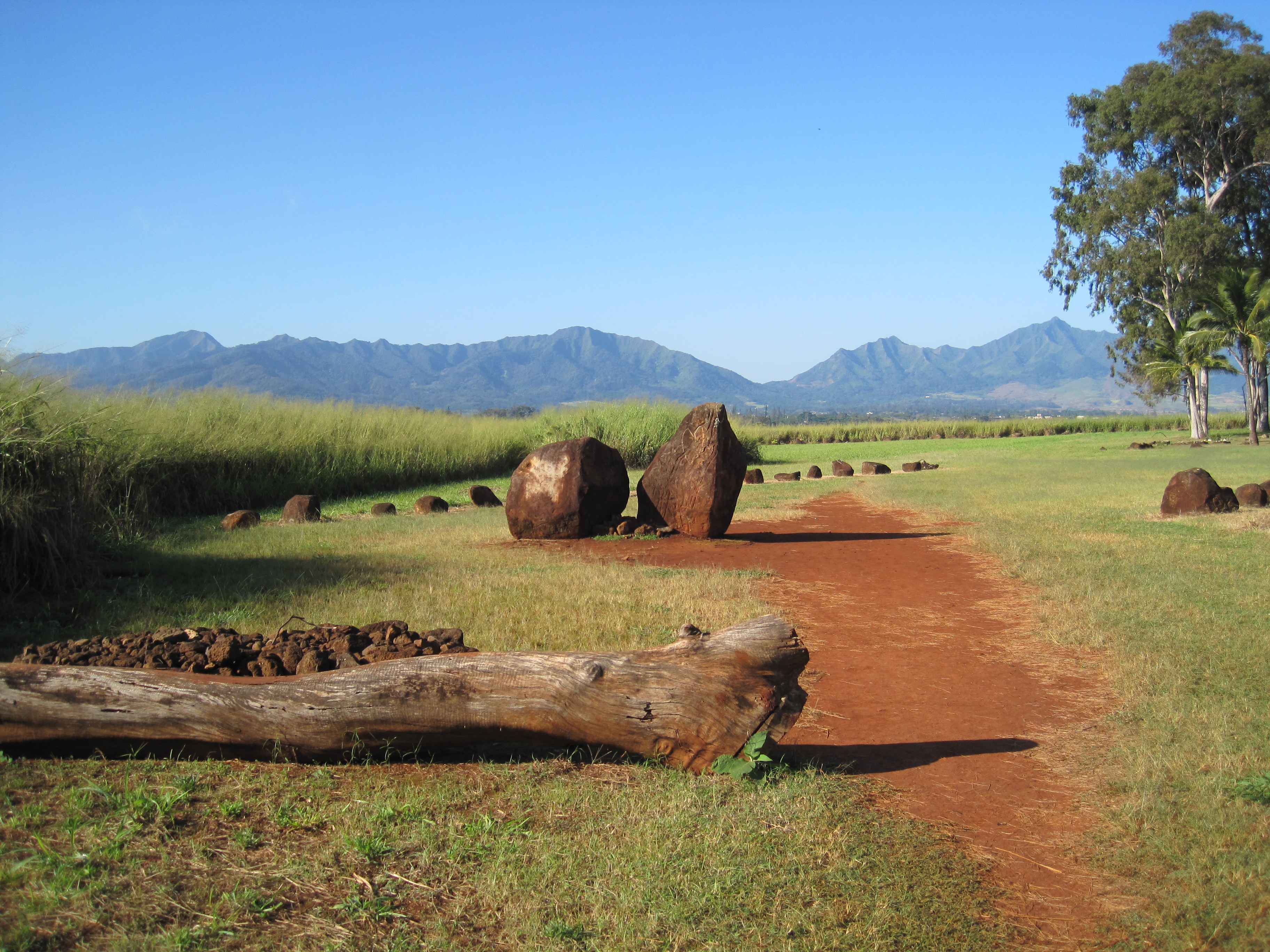 从入口方向看 Kūkaniloko 场地，背景是 Kolekole Pass 和 Waiʻanae 山脉的轮廓