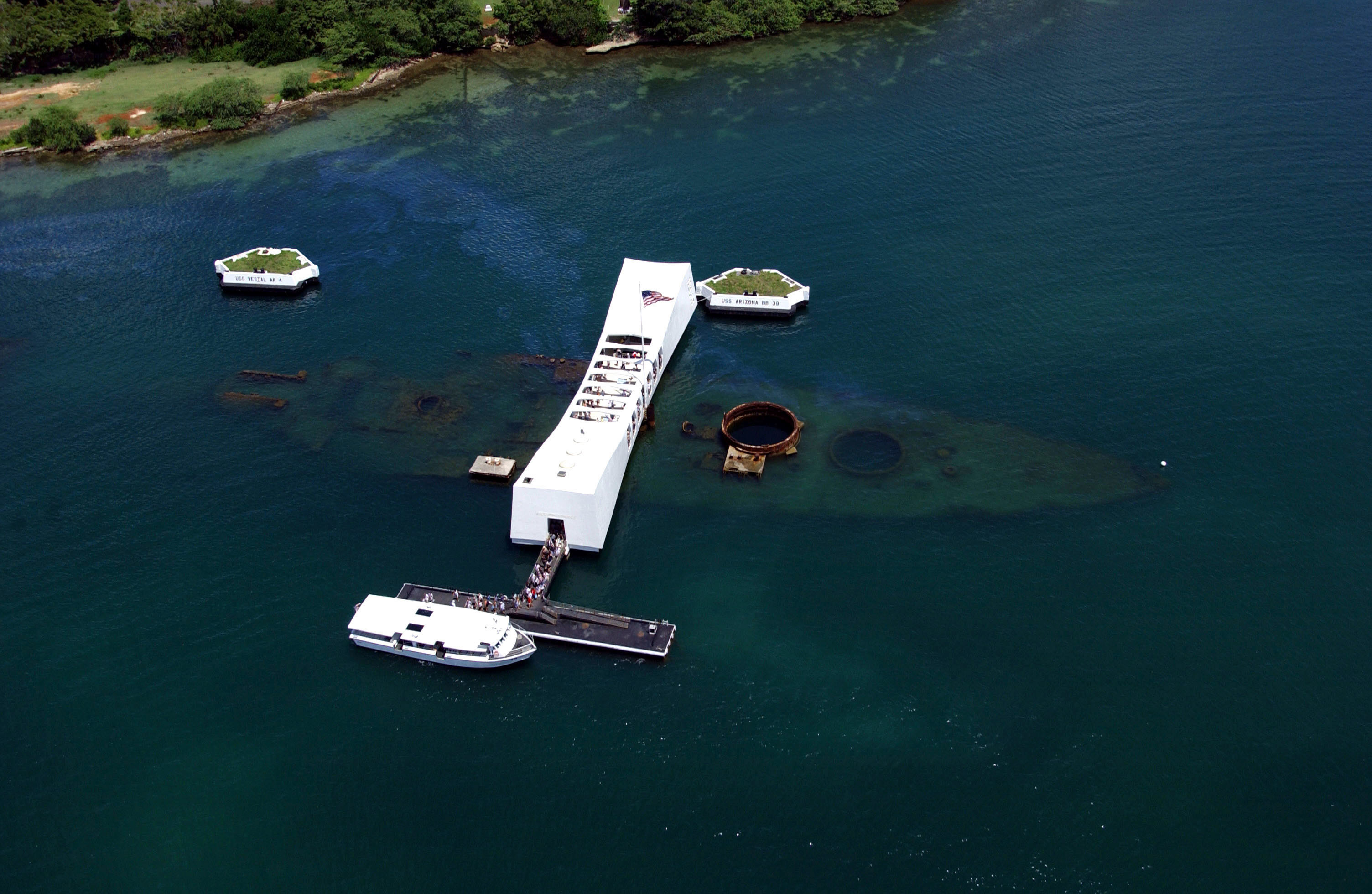 USS Arizona Memorial 俯视图，展示白色建筑跨在沉船上的空间关系