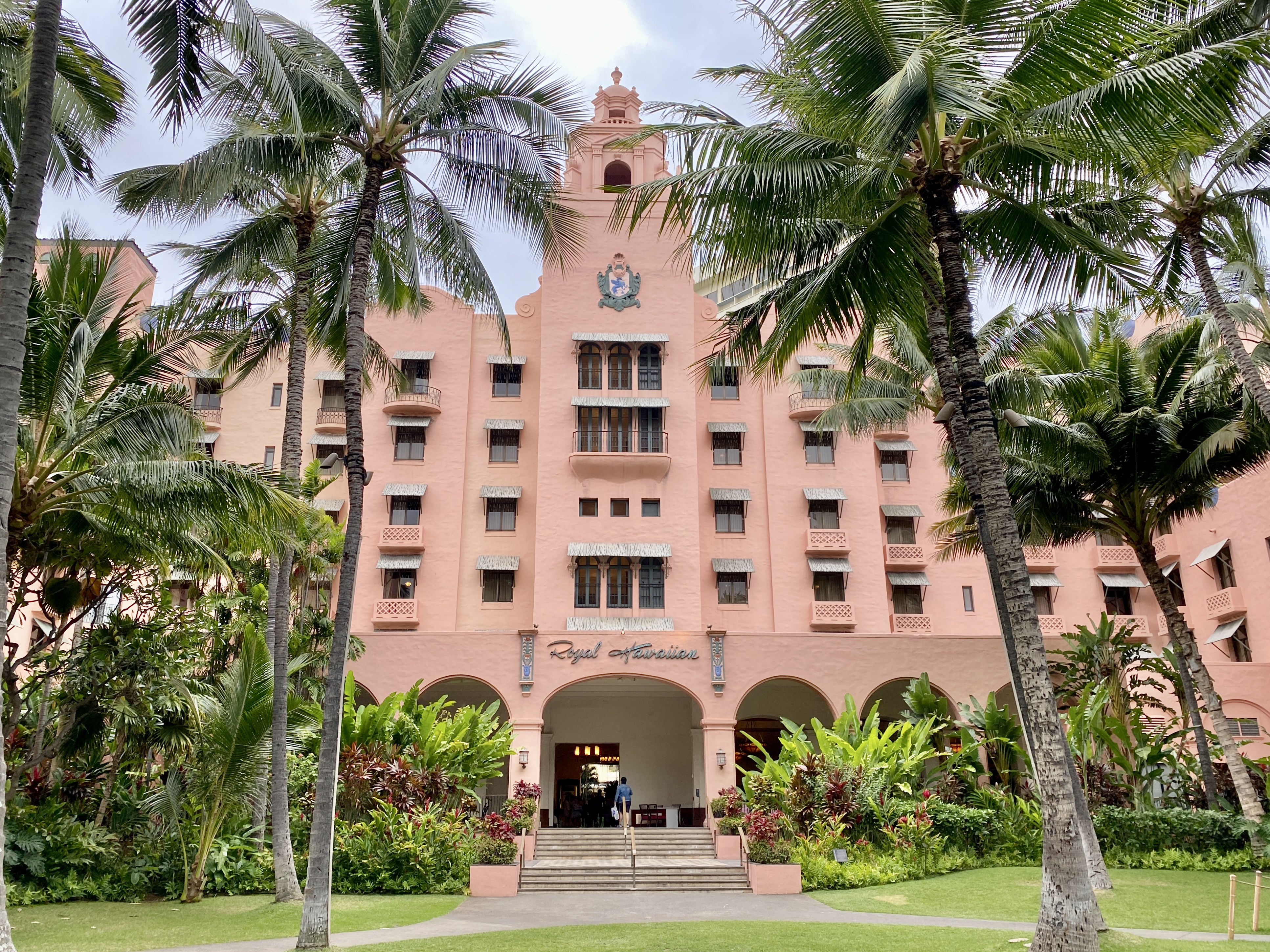 Royal Hawaiian Hotel 从 Kalākaua 方向的粉色 stucco、拱廊、塔楼和低坡屋顶