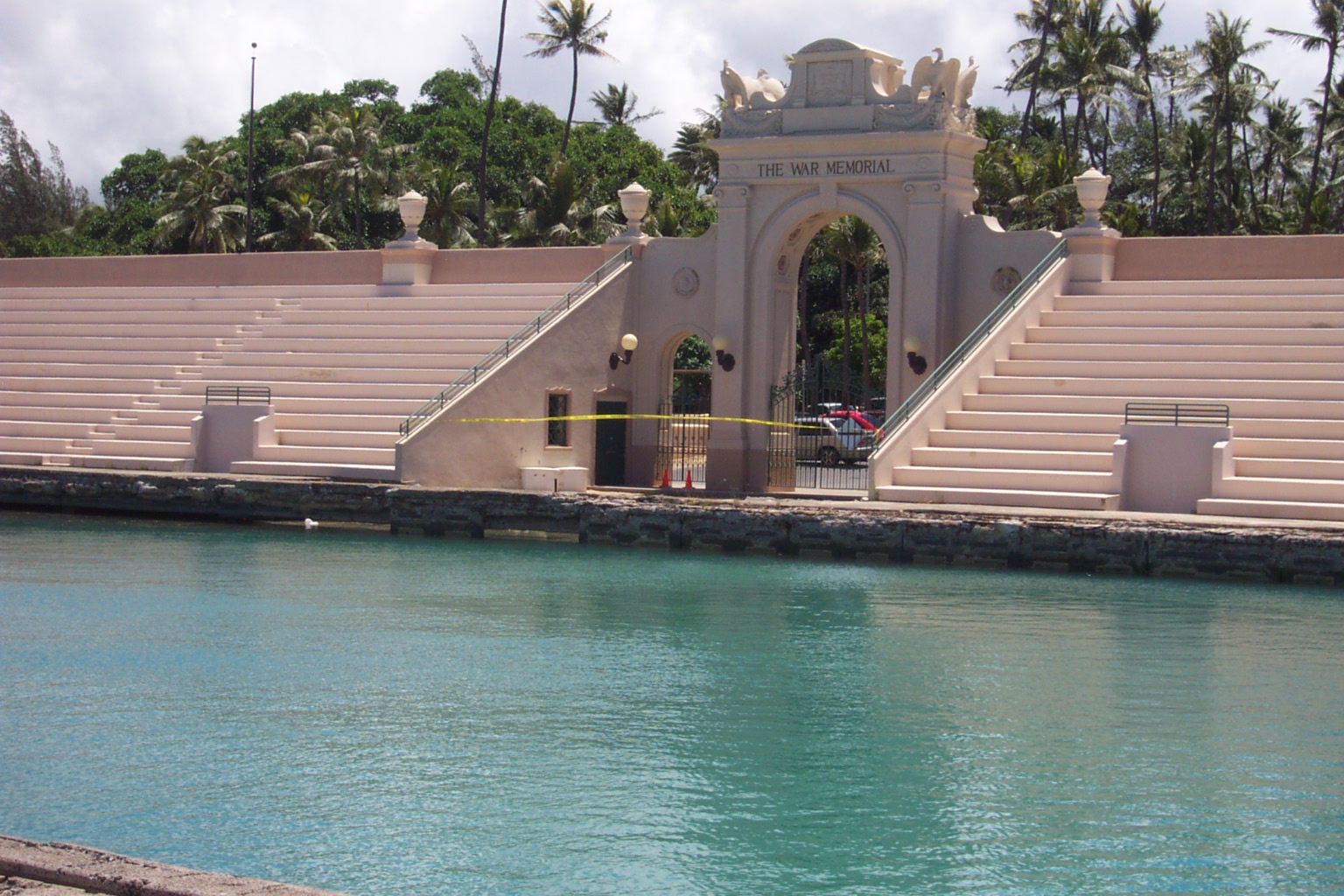 从 Kaimana Beach 侧看看台和池壁，可见看台、混凝土壁面和沙滩的相邻关系