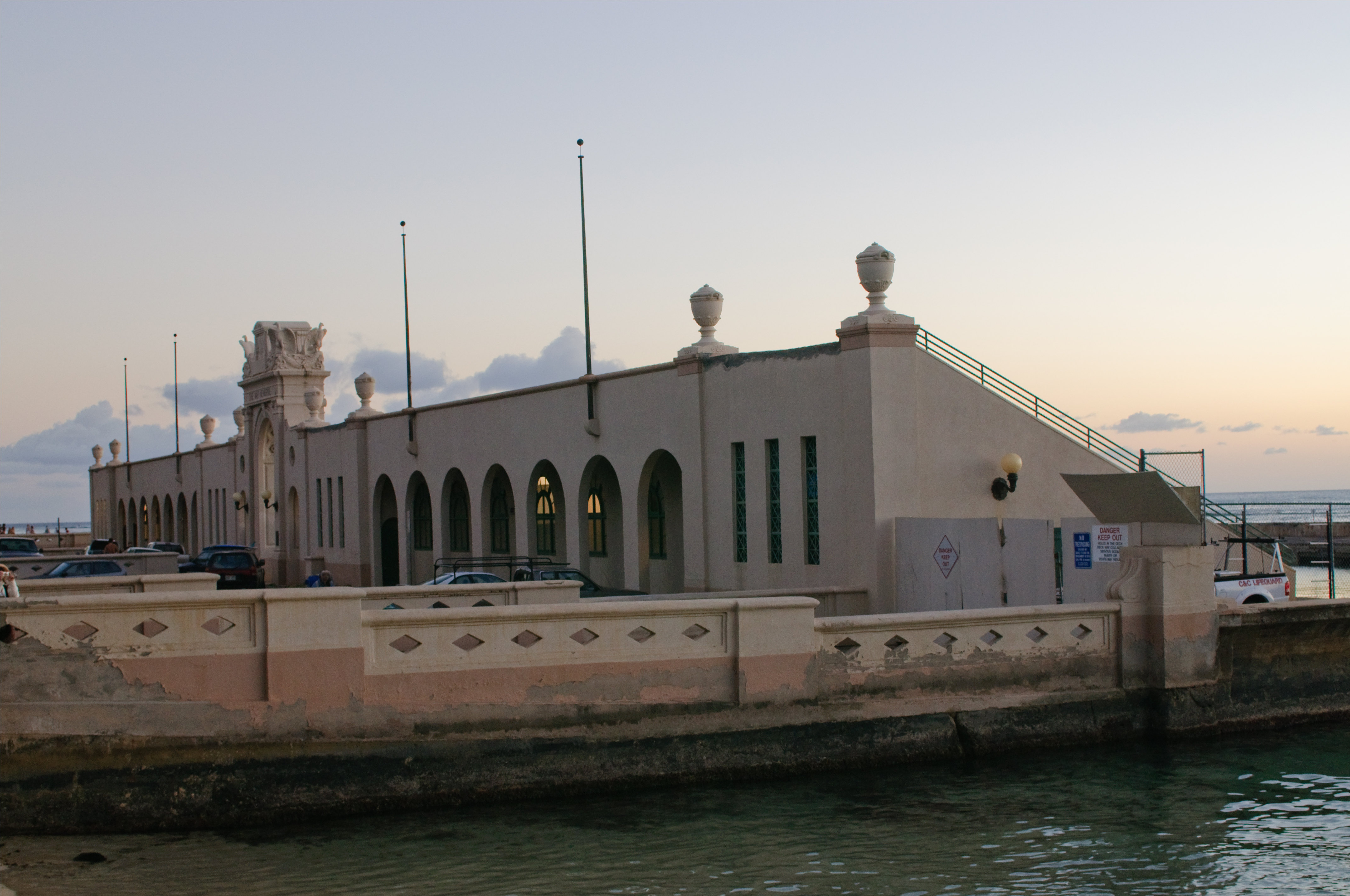 从 Kaimana Beach 方向看 Waikīkī War Memorial Natatorium，可见拱门、看台和泳池的序列关系