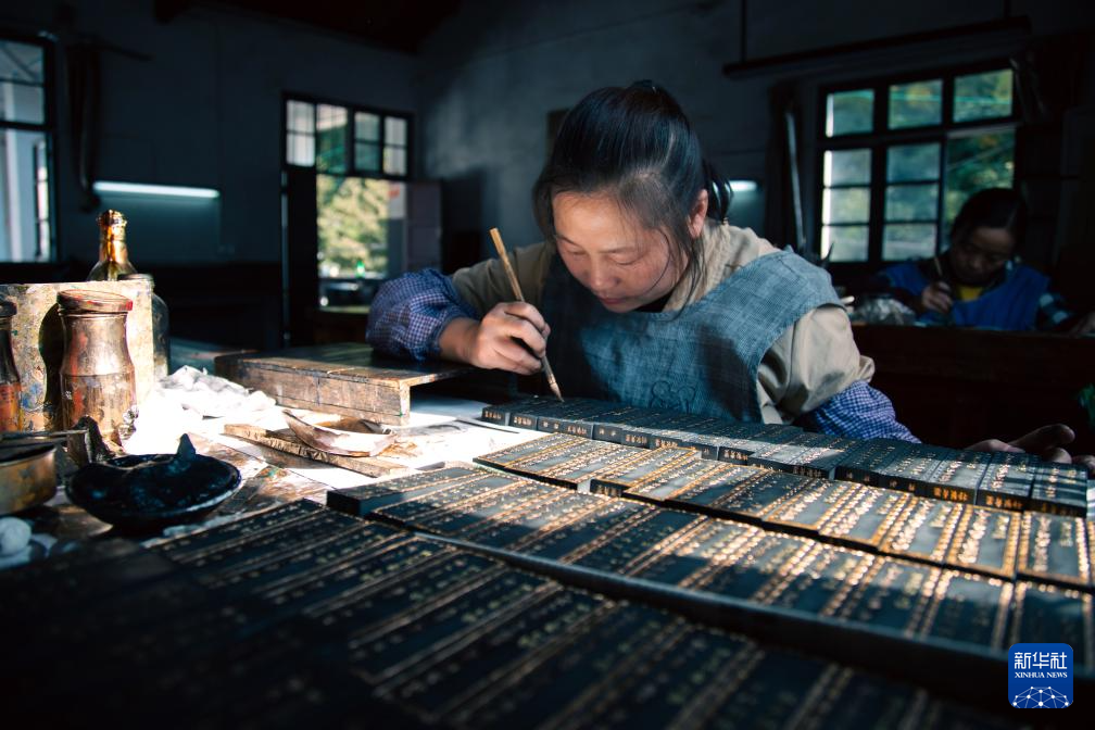 工人手持毛笔在墨锭上描金,墨面文字图案逐渐显现