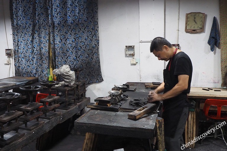 屯溪胡开文墨厂制墨车间内的场景,工人在工作台前翻打墨泥