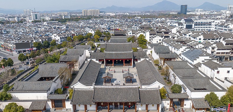 歙县古城徽派建筑群落，白墙黛瓦马头墙，远处群山掩映