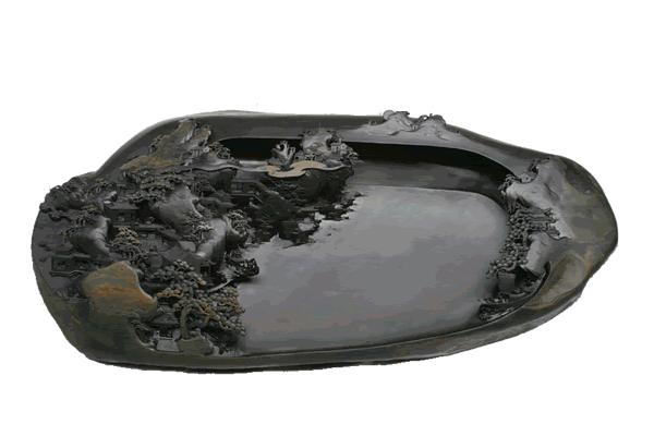 龙尾石歙砚雕刻成品，石面上精雕山水、松树和飞瀑图案