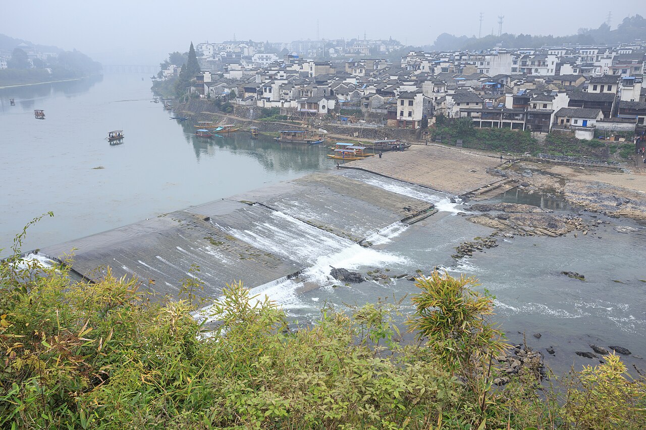渔梁坝全景，远处紫阳山和紫阳桥，近处坝体与停靠船只