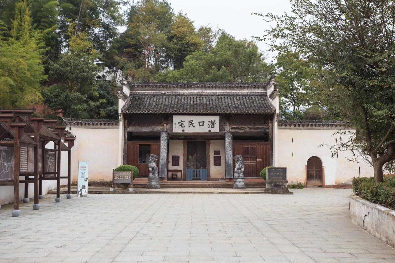 潜口民宅入口处石阶与石狮，山门掩映在绿树之中