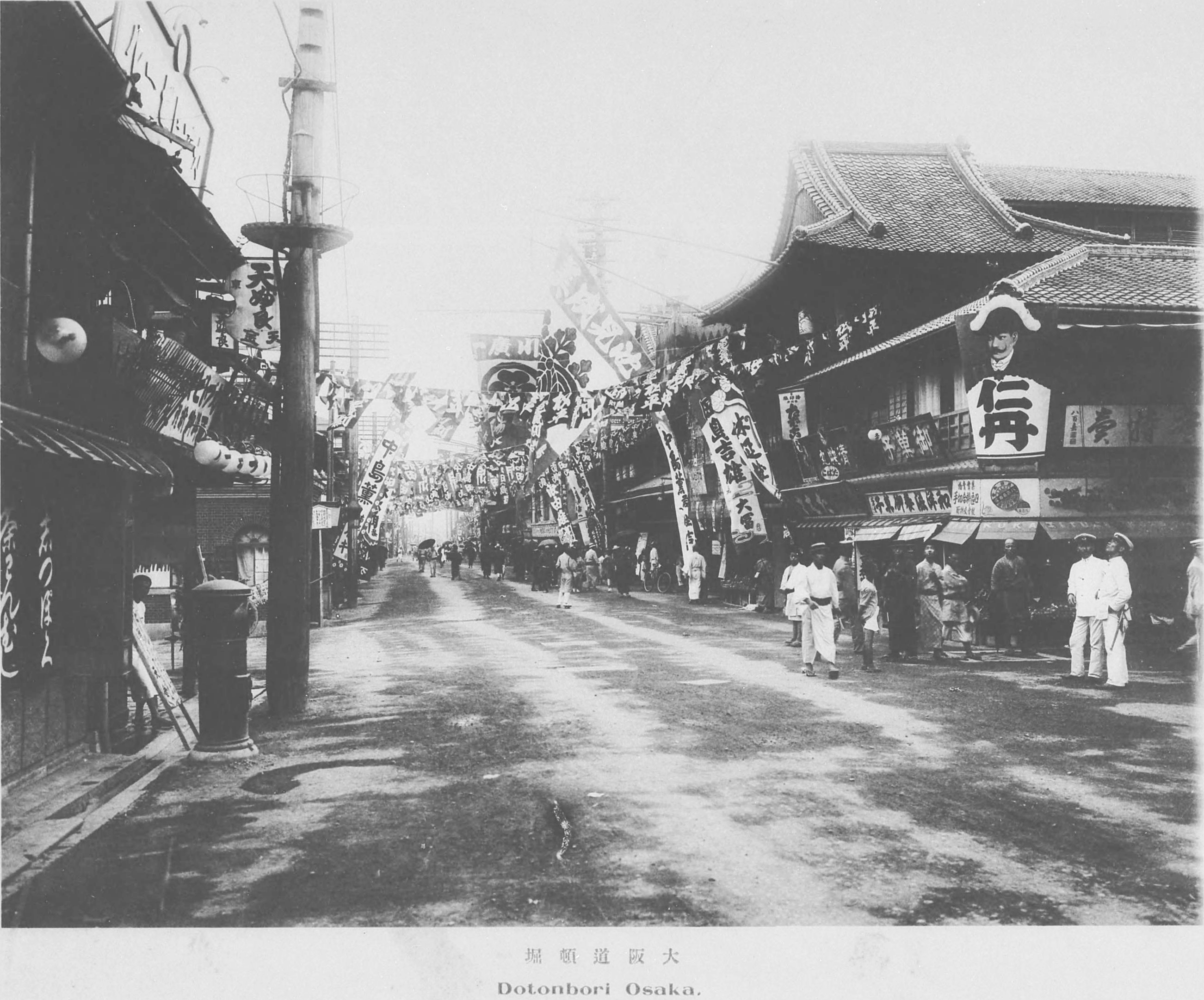 1910 年前后的道顿堀街景，旗帜和人群覆盖街道