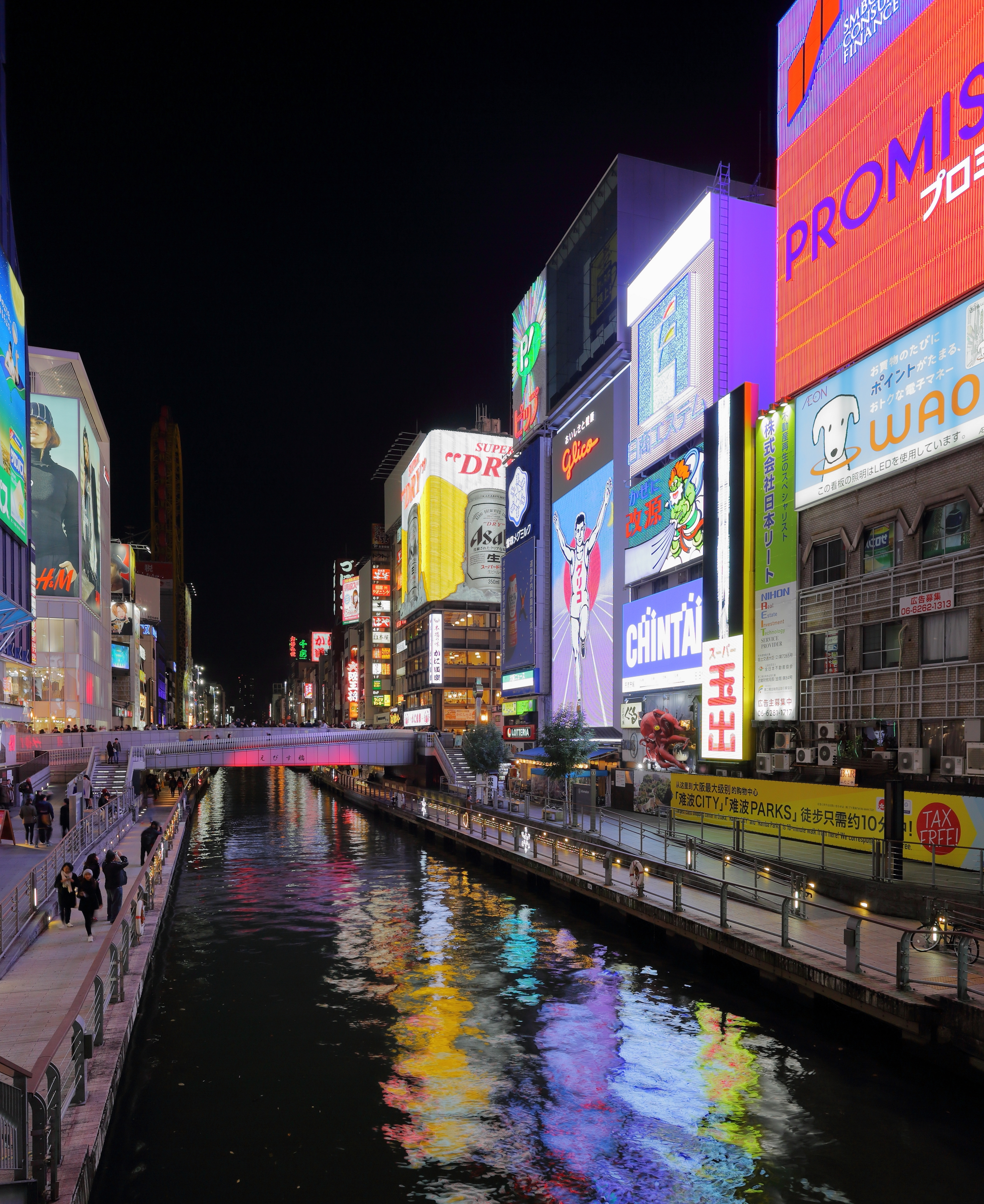 戎桥往前看的道顿堀夜景，格力高跑者和两侧招牌墙倒映在运河水面