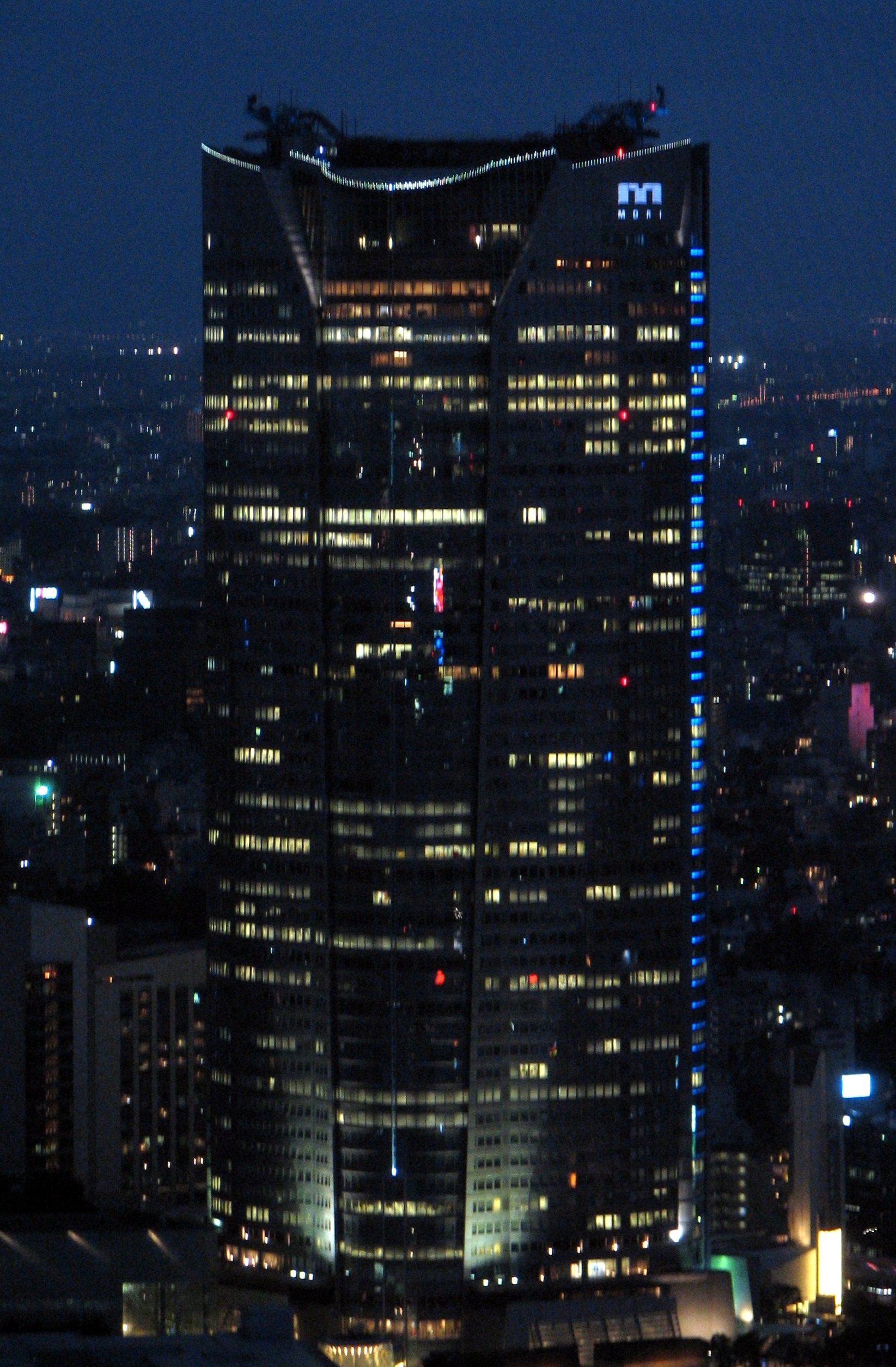 Roppongi Hills Mori Tower 夜间全景，从东京塔方向拍摄，展现了"城中城"在港区天际线中的体量