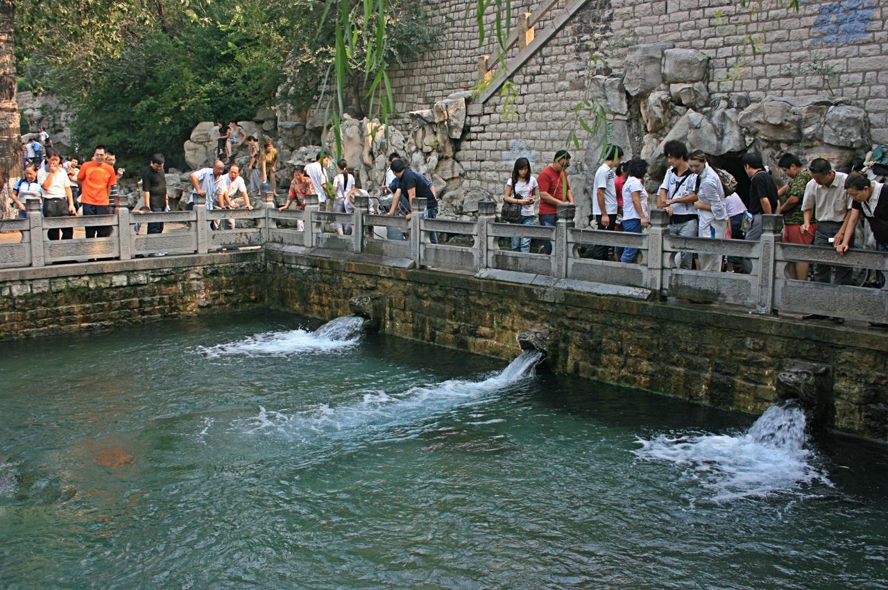 市民在护城河边的取水点排队接泉水，水桶规格各异