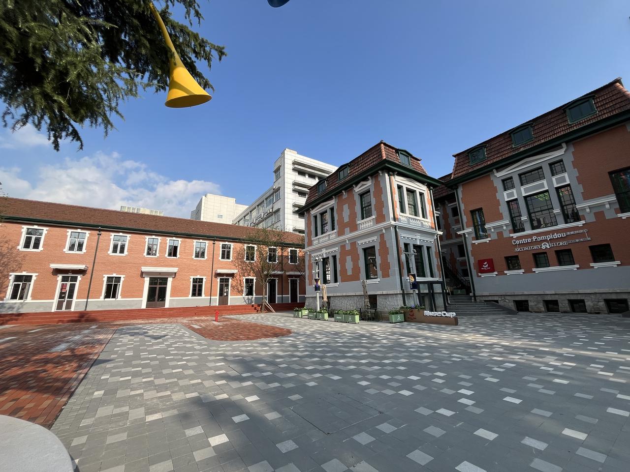 庭院一侧的建筑立面：红砖墙体、孟莎式屋顶和蓬皮杜中心标识