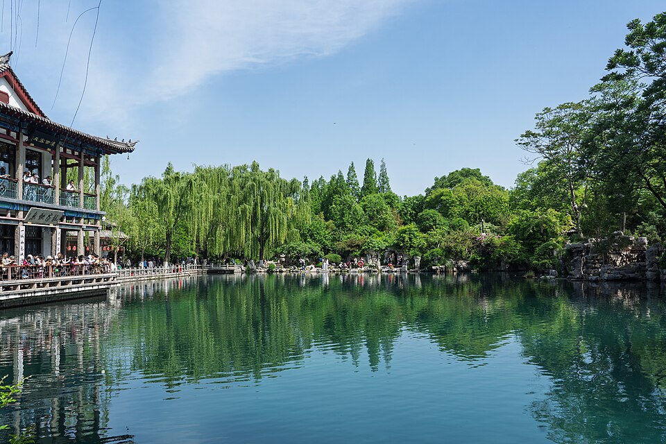 五龙潭主潭池全景，水面呈深碧色，岸边名士阁为二层仿古建筑