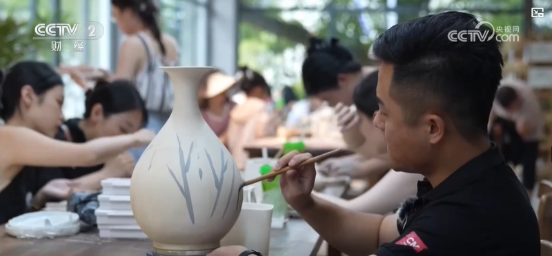 游客在孙公窑体验青花绘制，非遗传承人站在旁边指导