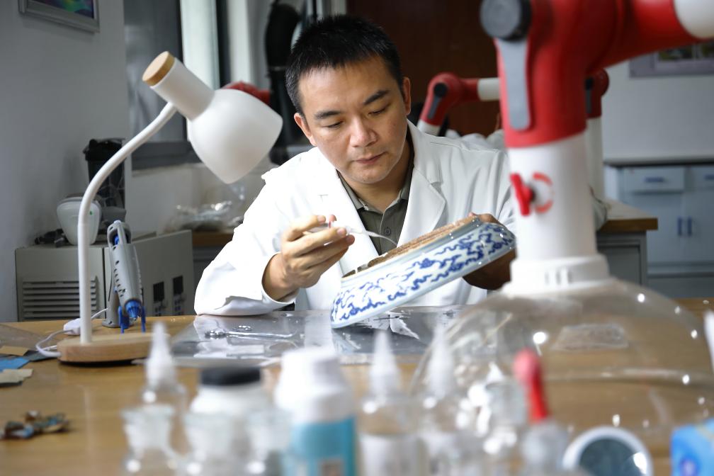 御窑博物院修复研究中心内部,修复师在工作台前对出土碎瓷进行分类整理