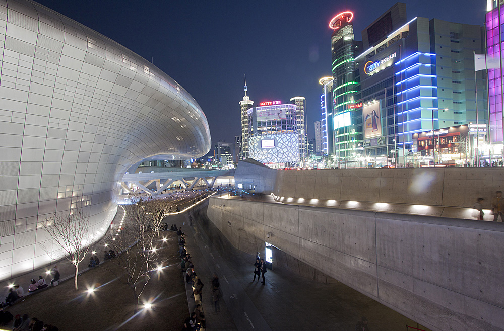 东大门设计广场与公园的整体夜景，银色曲面建筑和周边公共空间同时出现