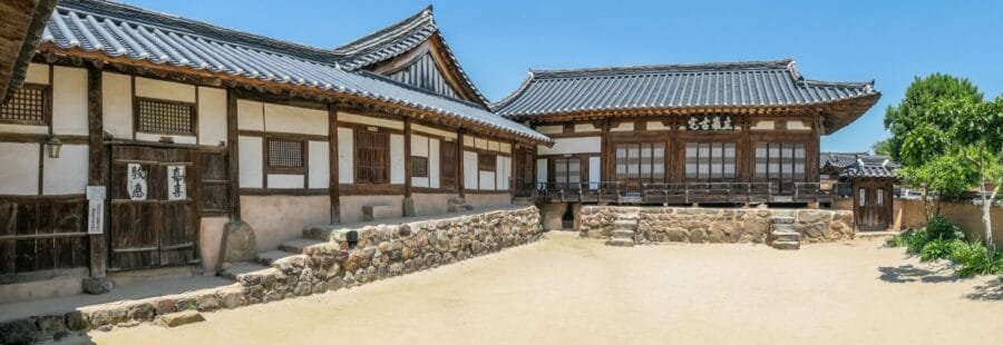 忠孝堂或北村里宅式的两班瓦顶大宅，深灰色陶瓦、挑出的屋檐和抬高的木台基是贵族的建筑标记