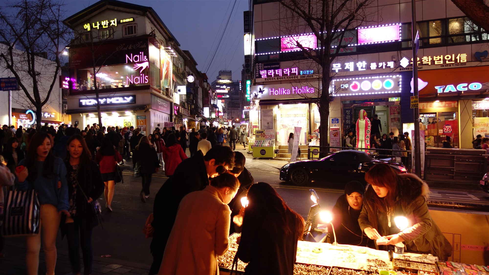 弘大夜间步行街，人群在霓虹灯招牌下穿行