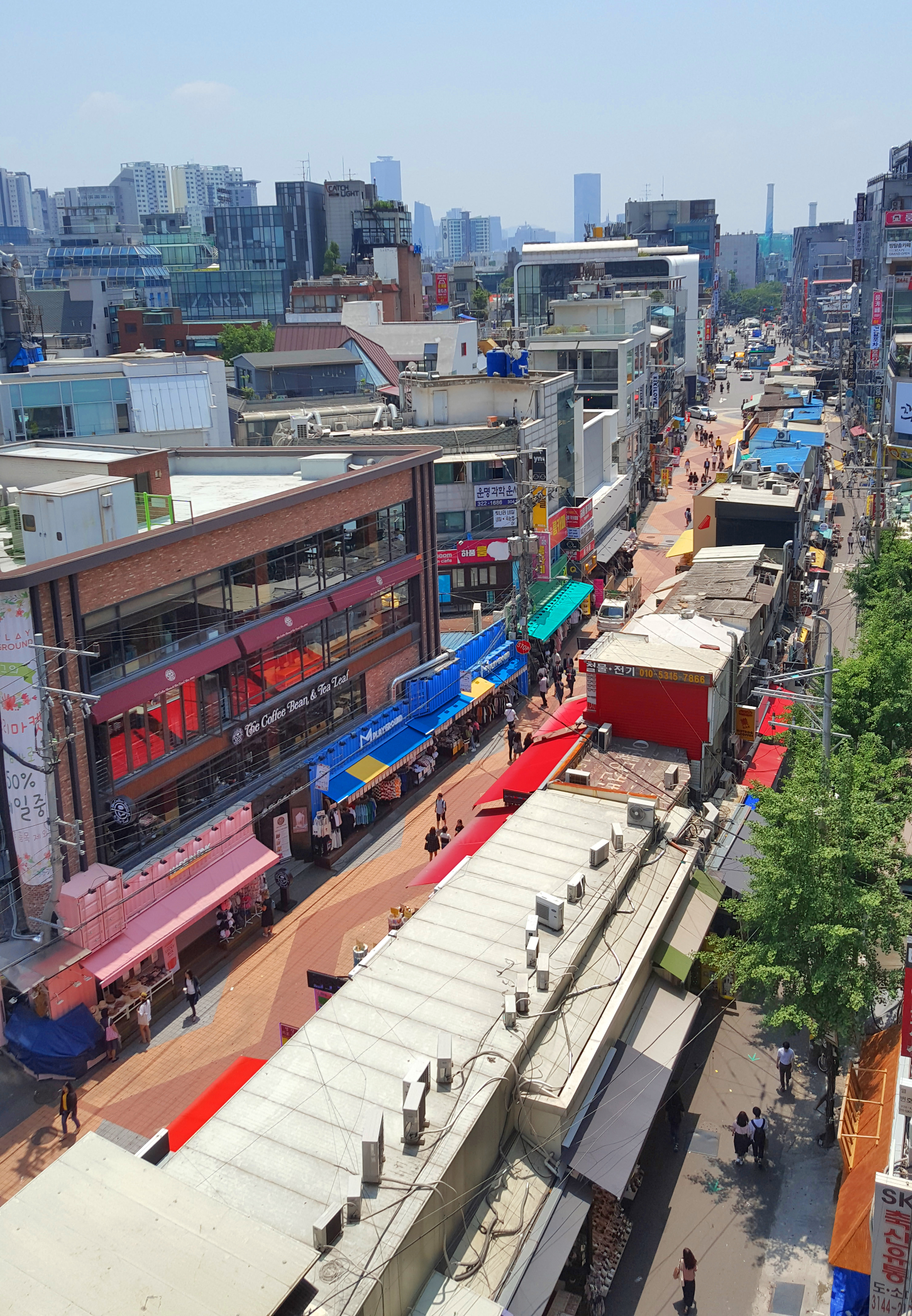 弘大白天街景，店铺招牌密集排列