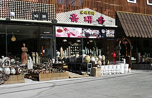 利川陶瓷村沿街工坊，展示柜内陈列着各类陶瓷器皿，开放式工坊门口能看到工匠工作的身影
