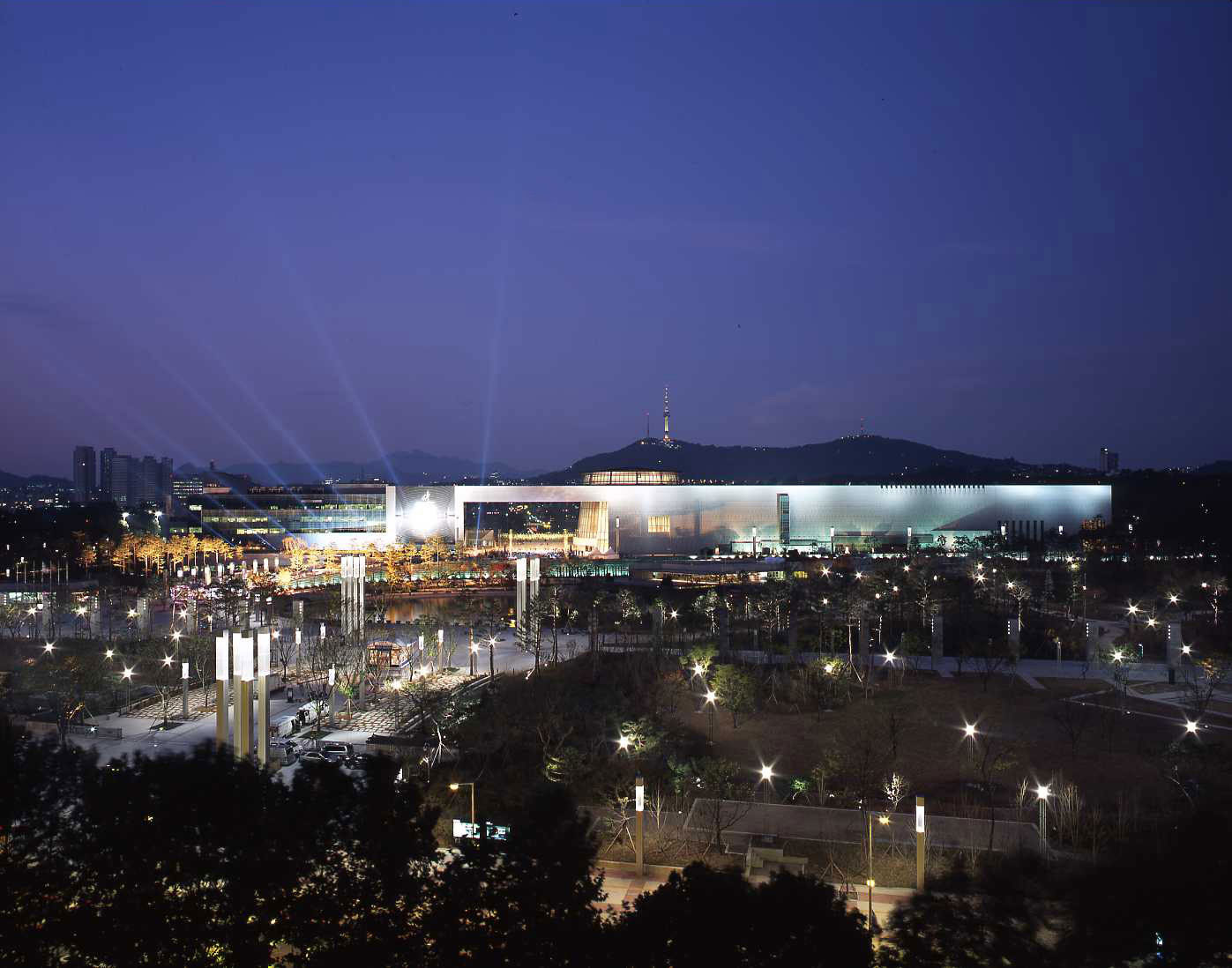 NMK 建筑全景，前景为 Mirror Pond，建筑完整倒映其中，北侧 Namsan 隐约可见