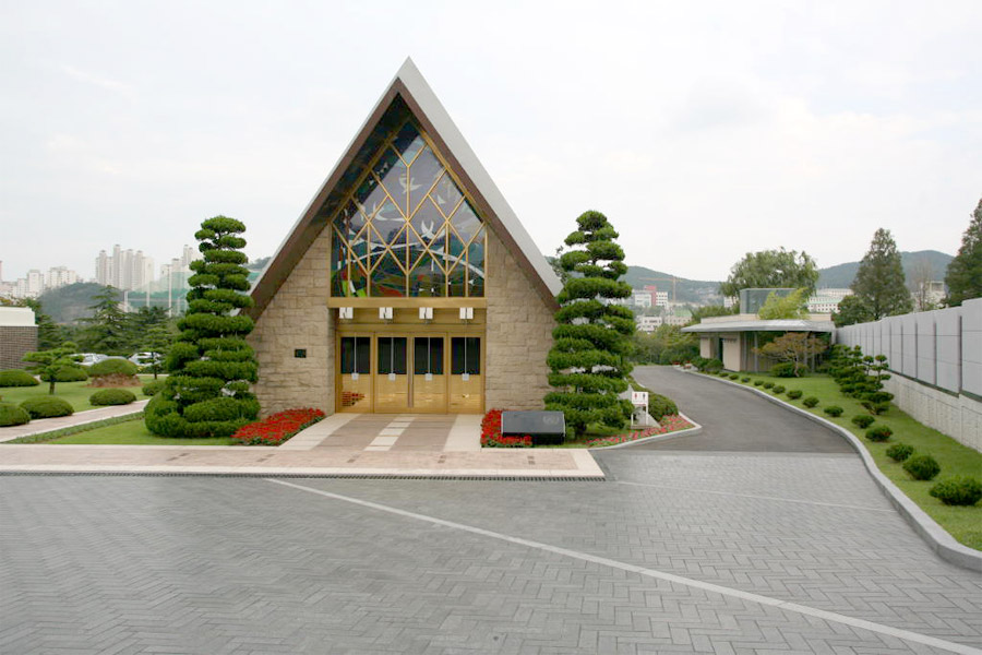 釜山 UN 纪念公园入口处的东方风格正门，八根石柱支撑歇山青瓦屋顶，门额上有韩文名称