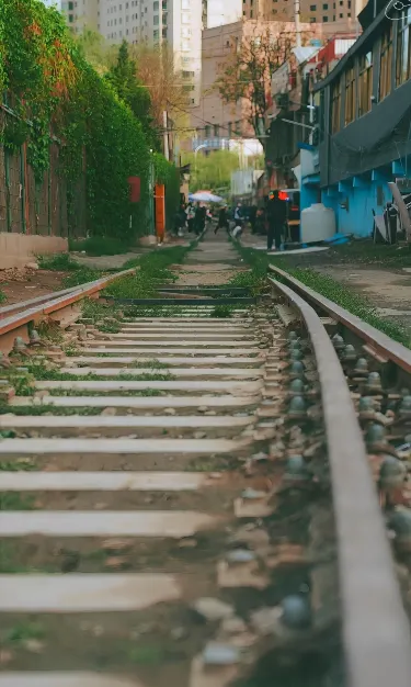 A set of railway tracks running through an urban area with buildings, shops, and