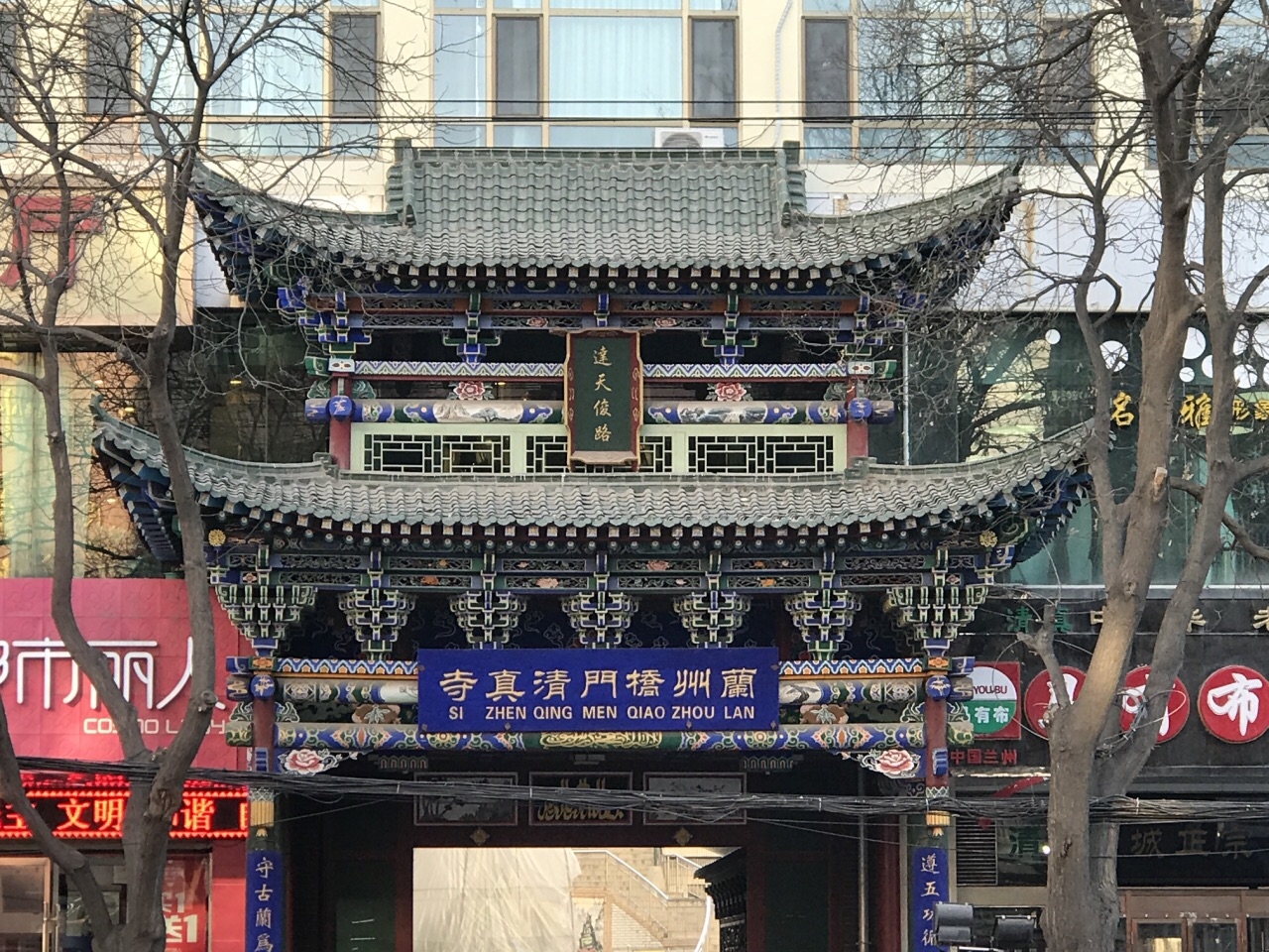 桥门清真寺大门，传统中式门楼悬挂烫金竖匾，八字墙砖雕花卉