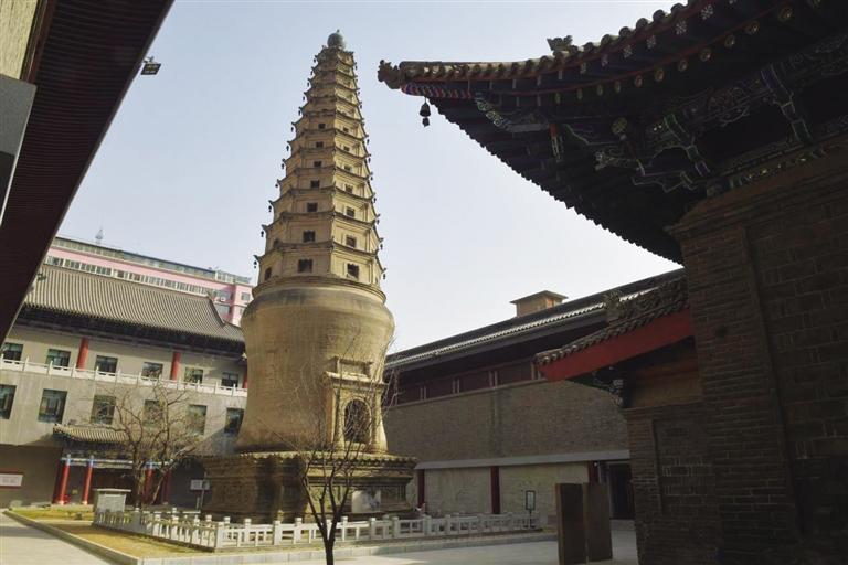 A tall, ancient pagoda stands prominently beside traditional Chinese architectur