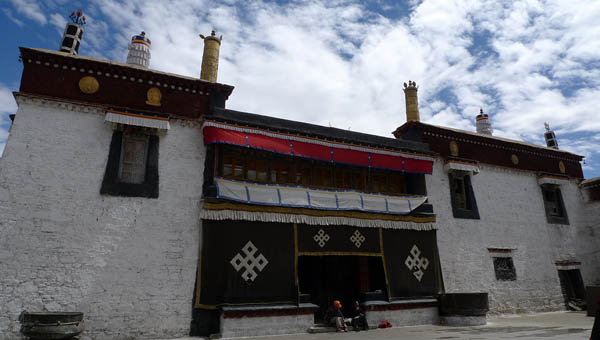 下密院的白色建筑外观，悬挂织锦经幡