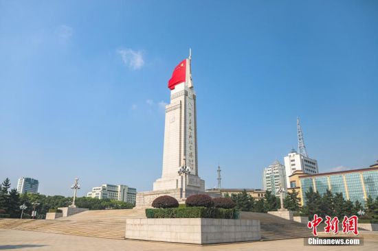 八一南昌起义纪念塔远景,塔身在蓝天与城市建筑背景下矗立