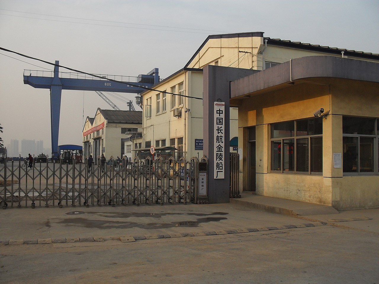 宝塔桥东街看金陵船厂，道路一侧是围墙上方露出龙门吊