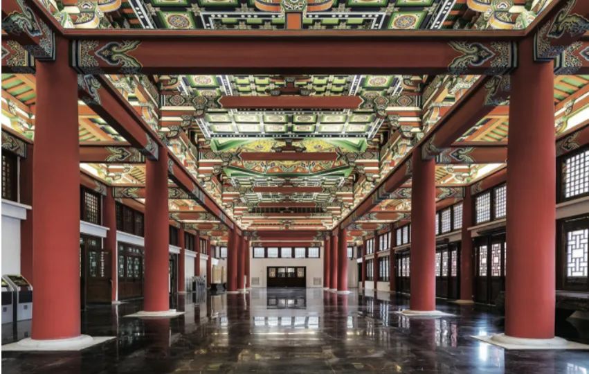 老大殿内部的水磨石楼梯与彩绘梁柱，展示传统木构装饰语言与钢筋混凝土结构的融合