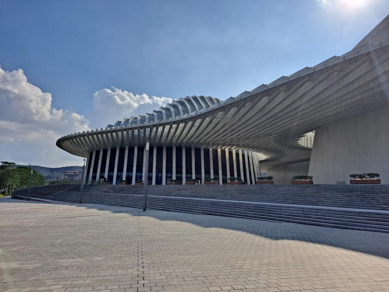 建筑前广场台阶和入口，屋顶折叠铝板结构清晰可见