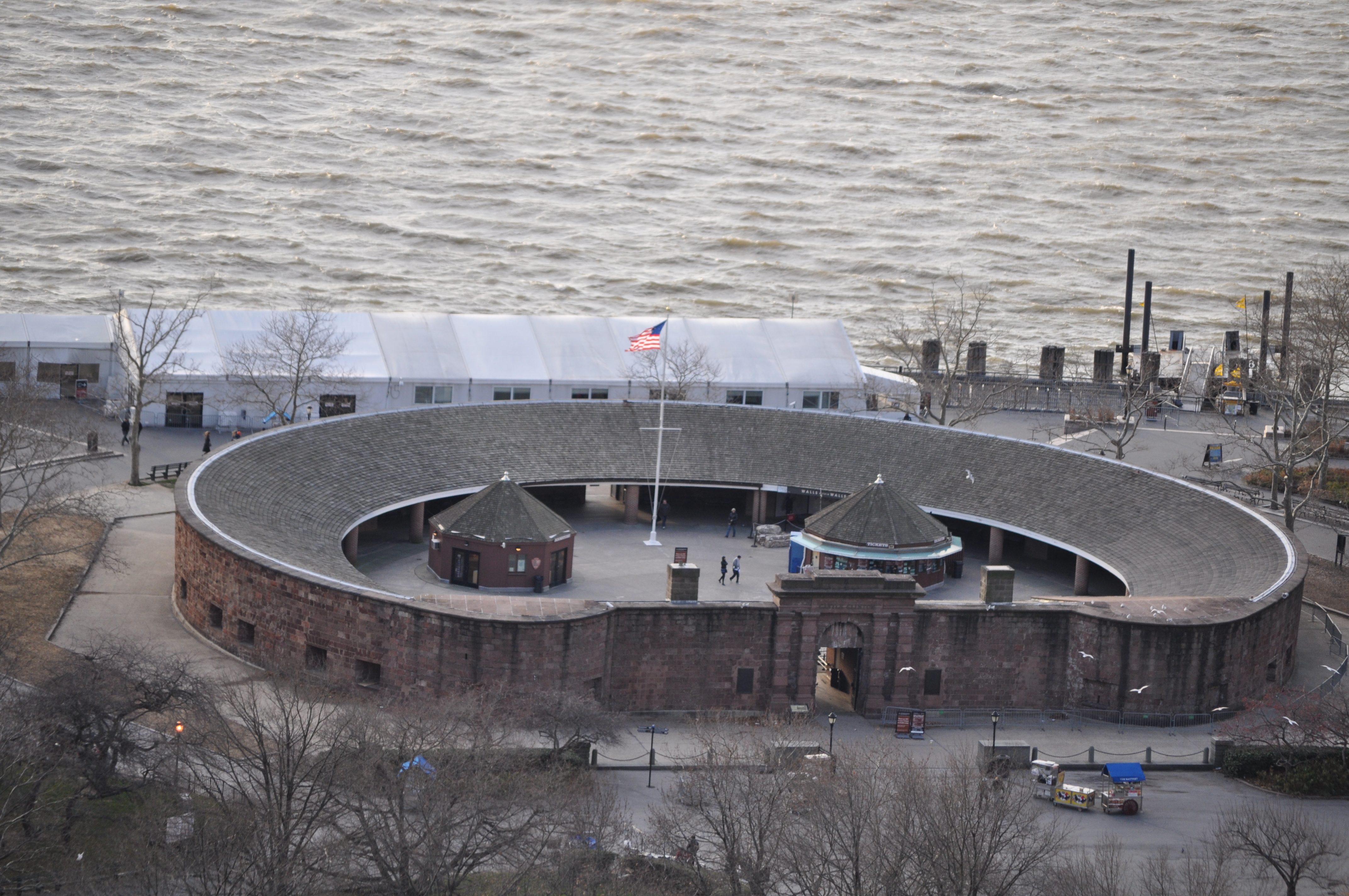 Castle Clinton 正面远景，可见圆形红砂岩外墙和公园草坪