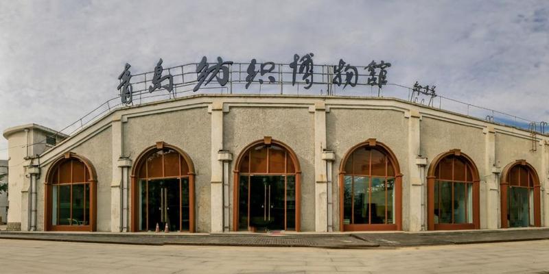青岛纺织博物馆入口建筑,弧形拱廊和深色框架构成工业风格立面