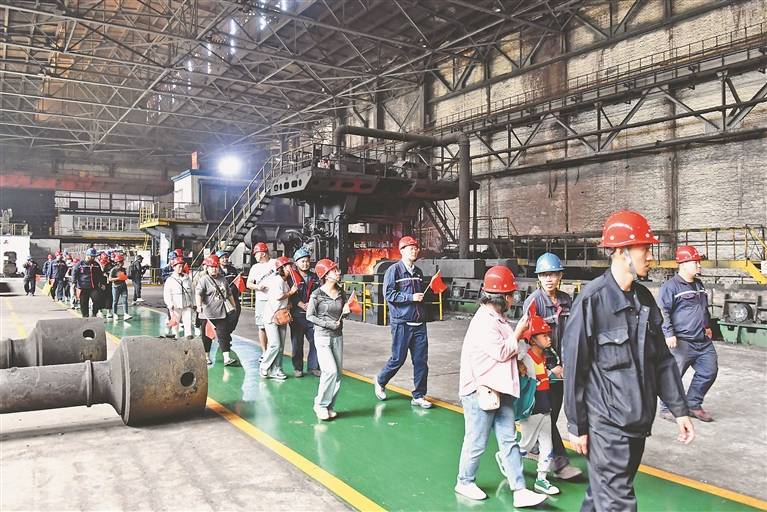 游客在厂内参观工业旅游，沿绿色参观通道行走