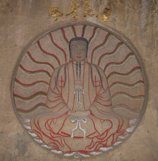 摩尼光佛造像特写：青石色面部、粉红色双手与灰白衣袍的天然三色