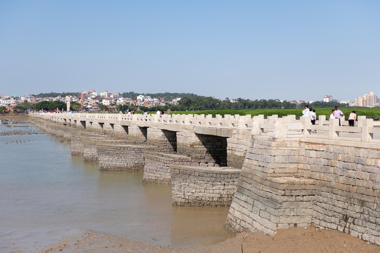 洛阳桥全景：长桥横跨洛阳江入海口，船形桥墩如排列的船头指向水流方向