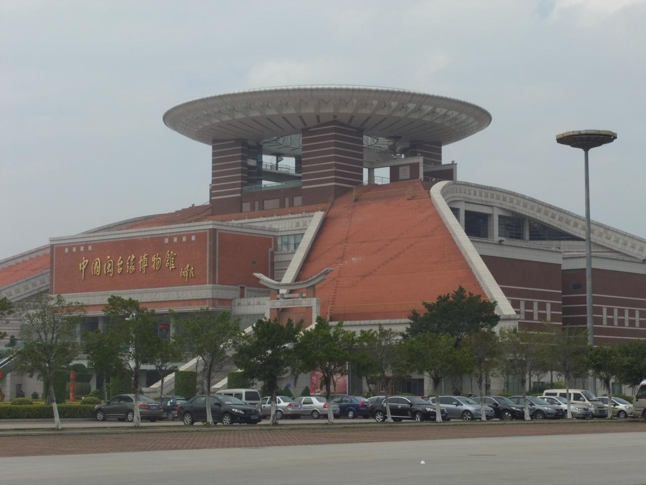 中国闽台缘博物馆建筑外观：红砖白石墙体与圆形观景天台，顶立金色和平莲