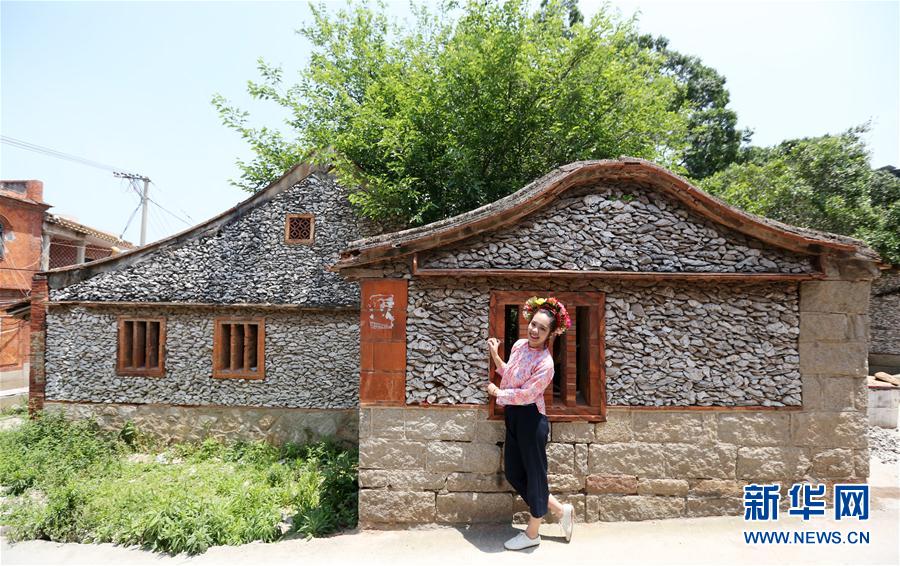 蟳埔村的簪花围体验：年轻游客身穿彩色仿古服饰、头顶花卉头冠在蚵壳墙前拍照