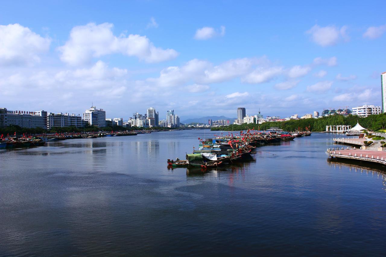 三亚河从市区穿流而过，河口处可见停泊的小渔船和两岸的现代高楼