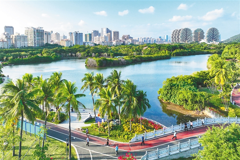 三亚河景观步道上散步的游客，几步之外就是停靠的渔船