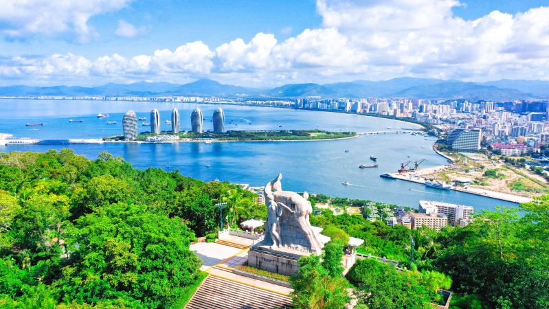 从鹿回头山顶向东南俯瞰榆林湾，U 形海湾水面开阔，远处可见军港码头和舰艇轮廓