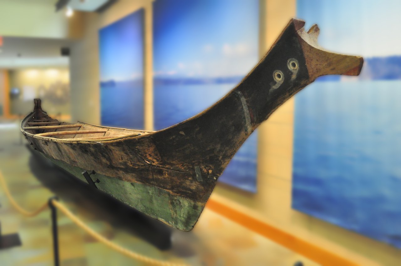 Canoe Hall 中的一艘 cedar dugout canoe（背景已模糊以保护他人肖像）