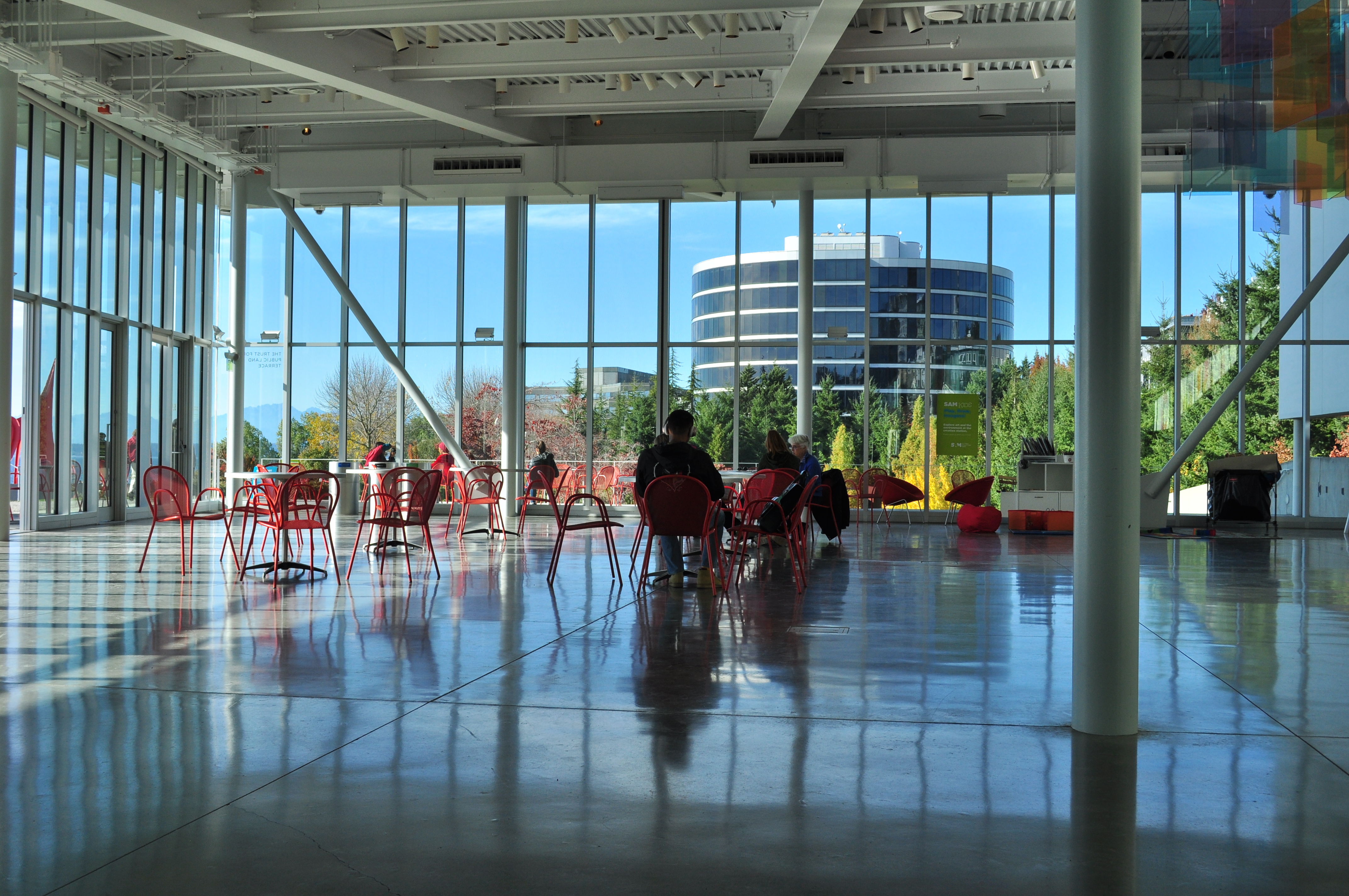 PACCAR Pavilion 内部：单层玻璃馆，背景是邻近的 Airborne Express 旧大楼立面