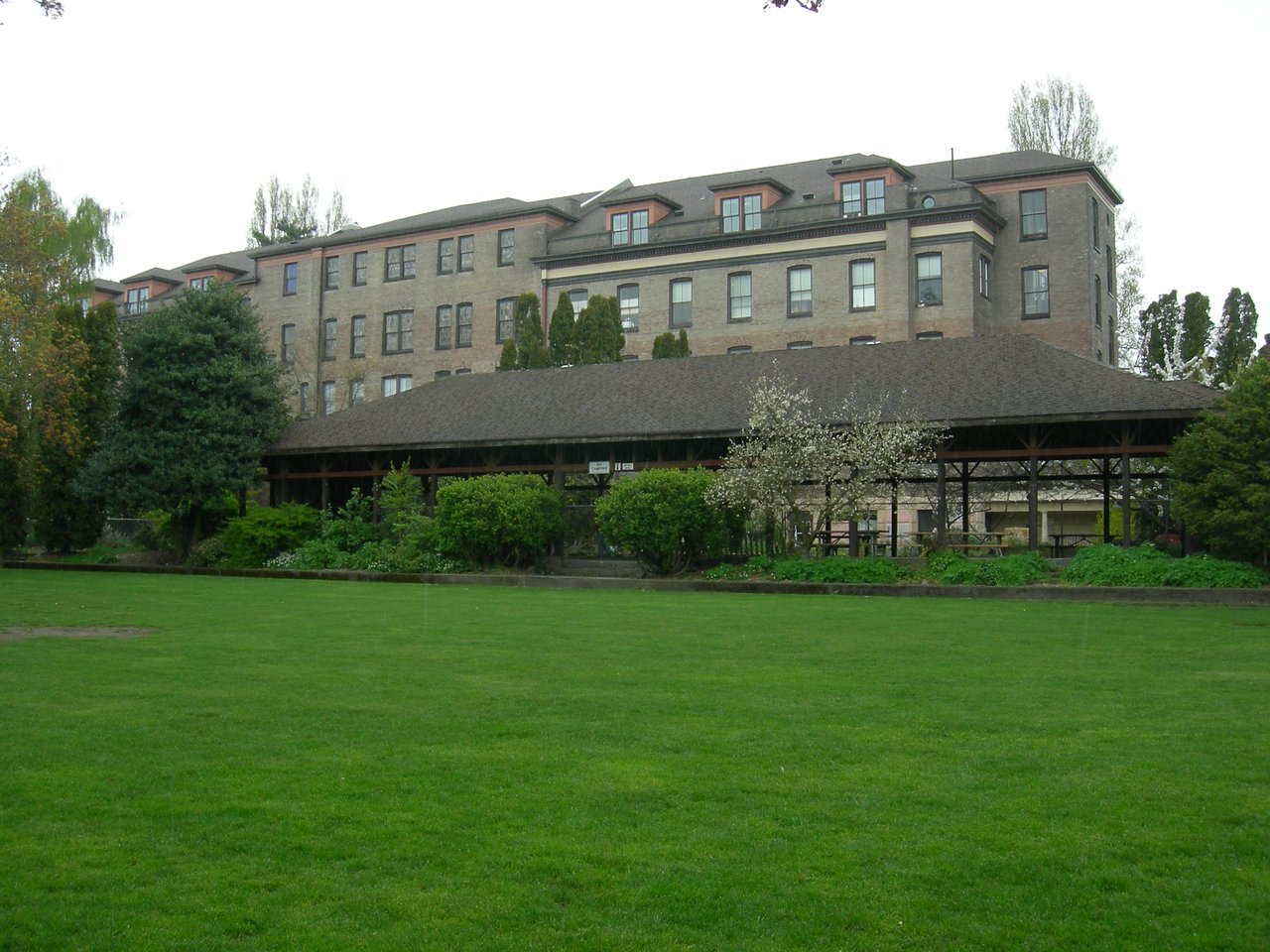 Good Shepherd Center 主楼后侧 Meridian Park 一面：砖墙、果园、草坪、儿童游乐区