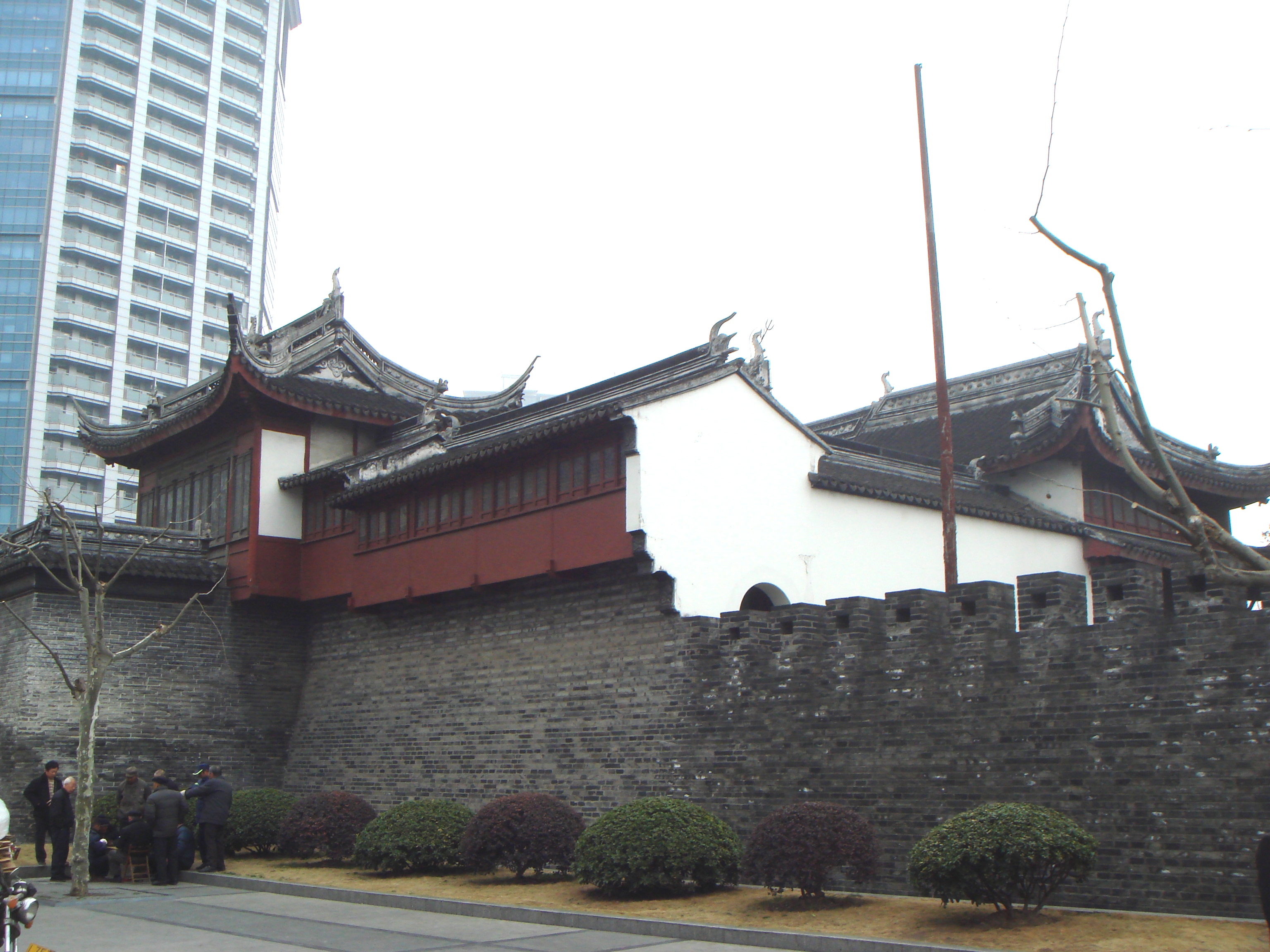 大境阁与残存城墙全貌，三层楼阁建于城墙之上，墙根紧邻人民路