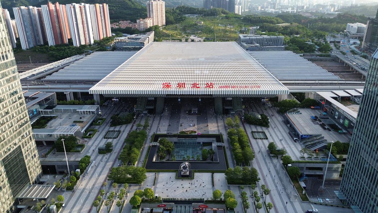 深圳北站航拍全景，波浪形屋顶覆盖11站台20股道，周边为新城开发