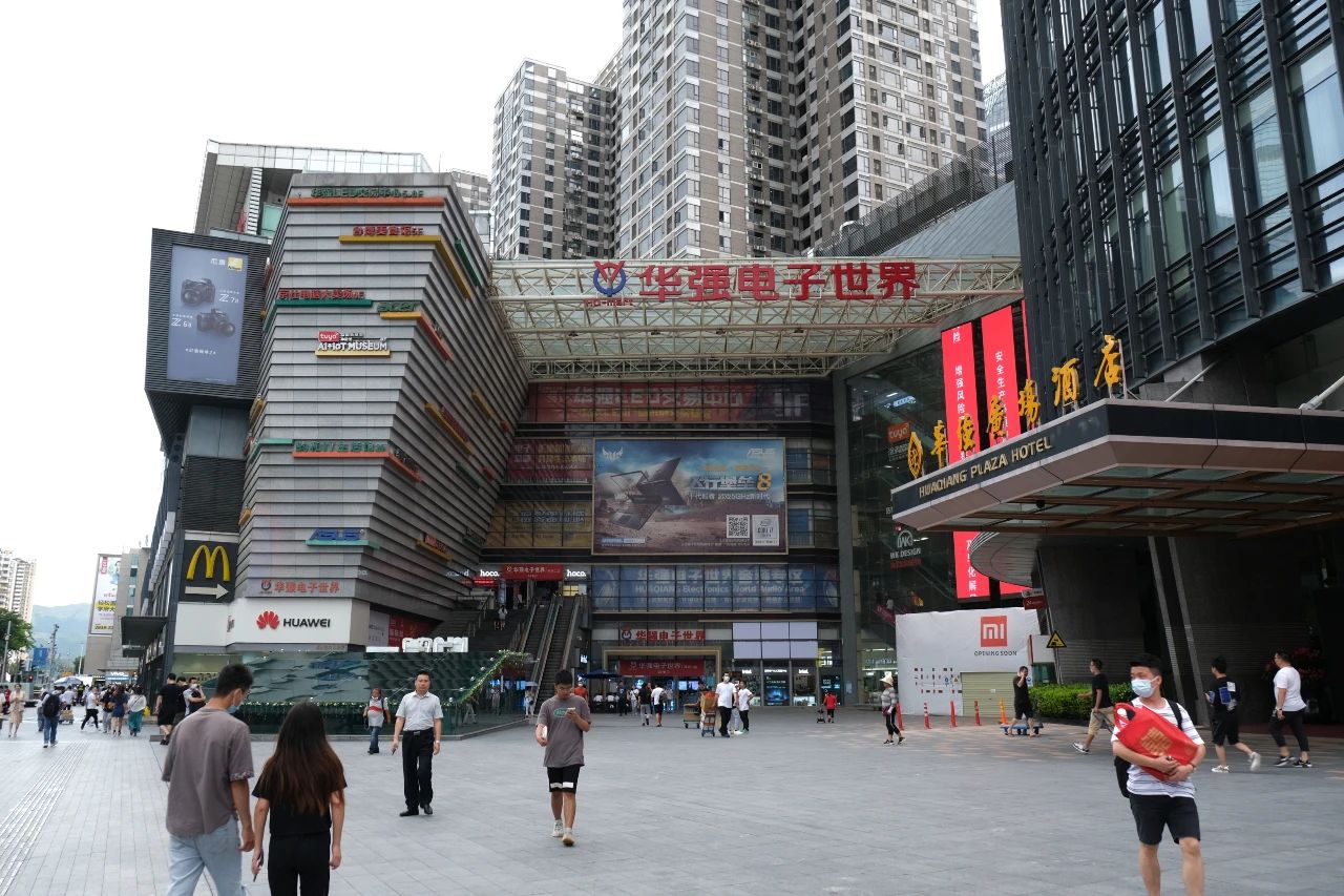 华强北街头的物流场景，板车和快递车在巷弄中穿行
